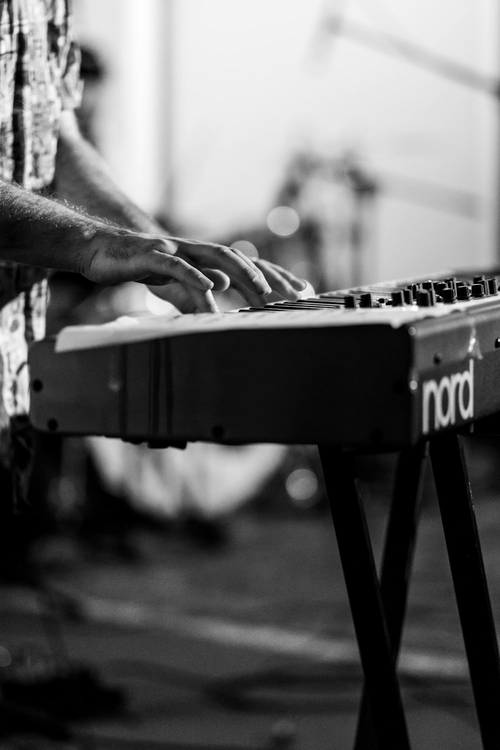 Foto en escala de grises de un hombre tocando el teclado electrónico