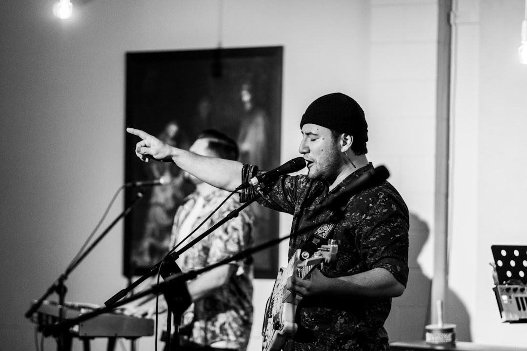 grayscale photography of singing man playing guitar