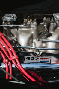 Close-up shot of a sleek Mustang engine bay featuring bold orange and red racing accents under dramatic lighting.