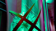 A vibrant metal wall sculpture featuring abstract shapes and bold colors, illuminated by soft lighting.
