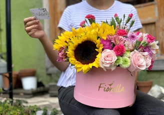 A cheerful customer holding a flower box styled like an old-fashioned Indian post box, smiling warmly.