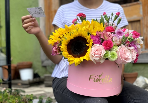A cheerful customer holding a flower box styled like an old-fashioned Indian post box, smiling warmly.