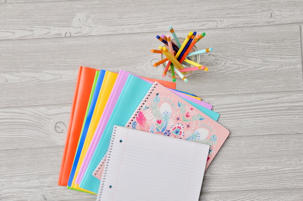 pile of assorted-color notebooks on brown wooden table