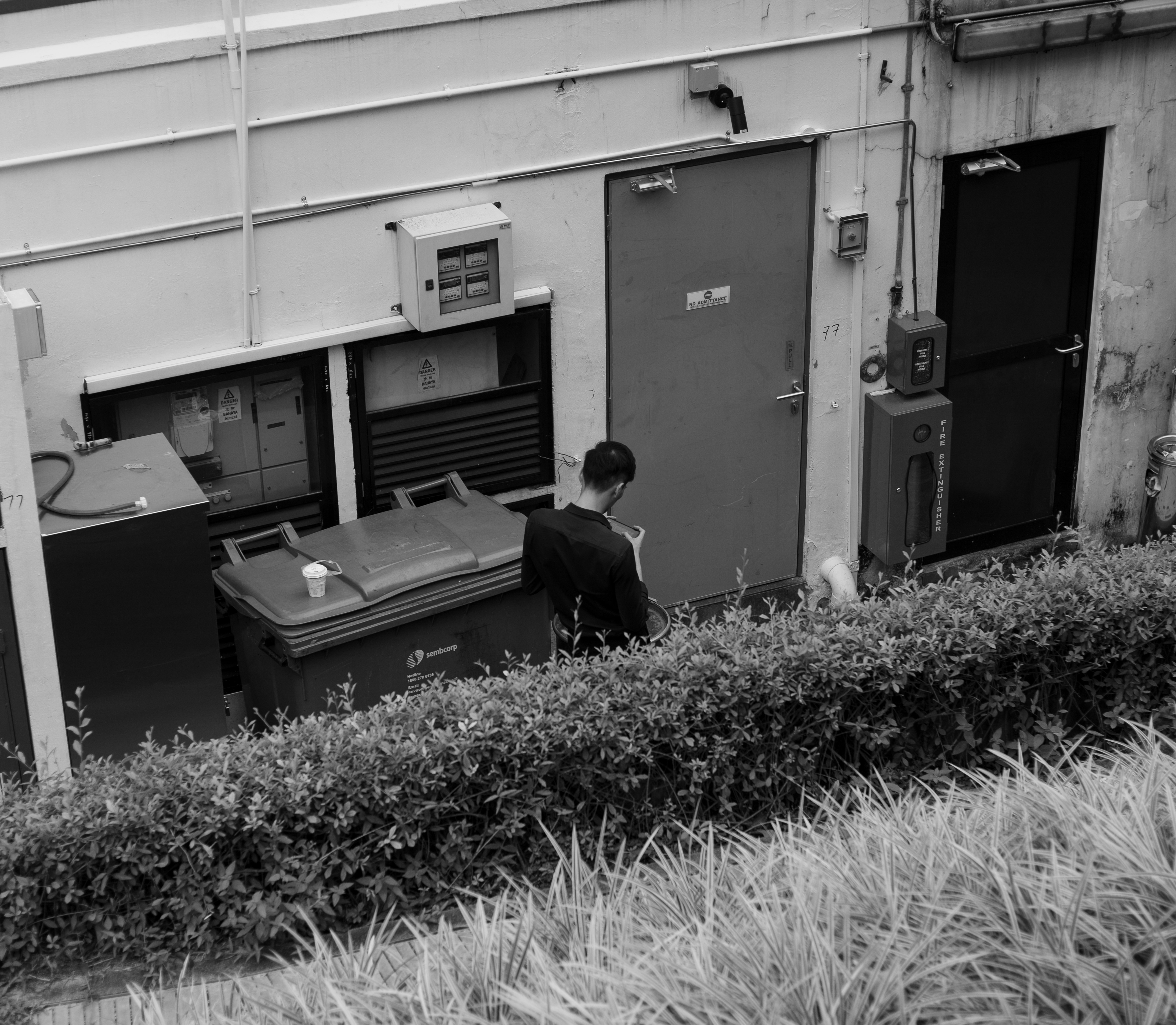 grayscale photography of man standing by a close door