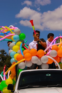 people on back of pickup truck with balloons