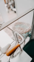 A decorative, miniature bicycle with a woven basket attached is placed near a window. The bicycle features a white seat and orange handlebars, with detailed metal work and lace decorations near the basket.