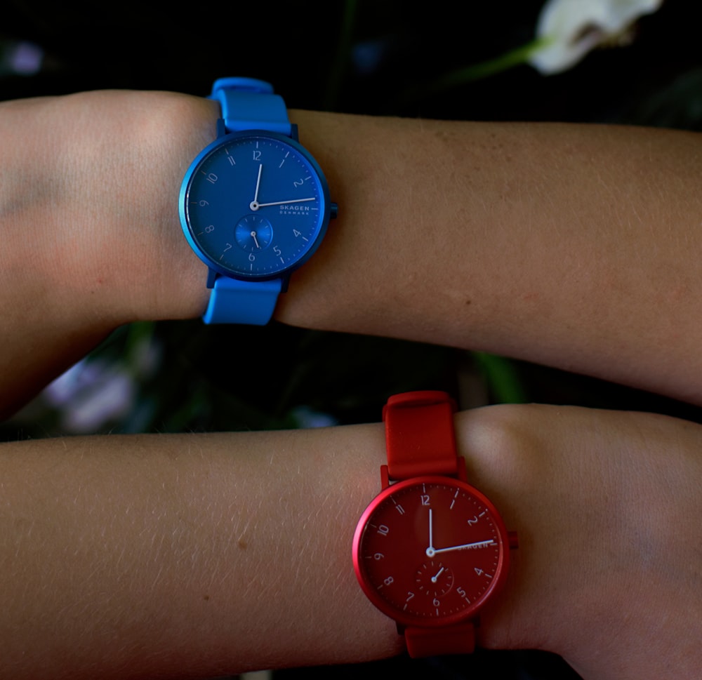 person wearing round blue analog watch displaying 12:14 time