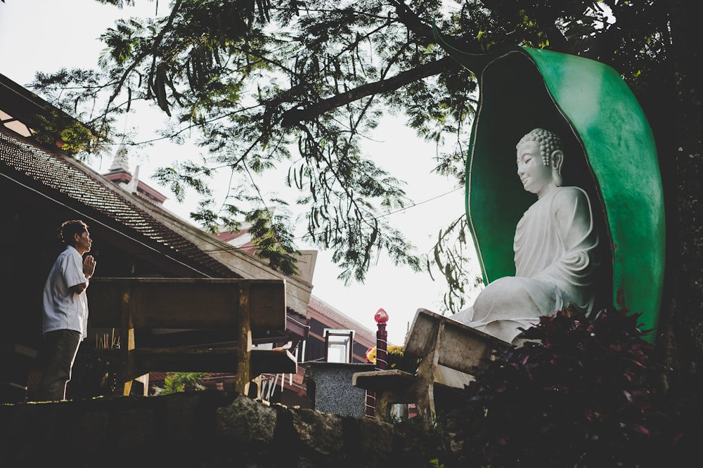 man praying in front of Buddha statue