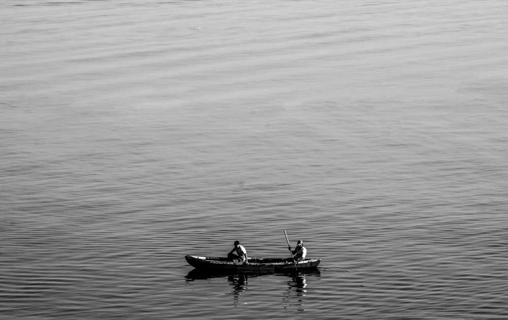 grayscale photo of two person sitting on boat