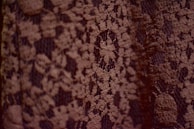 Detailed image of a delicate lace pattern being carefully sewn by hand.