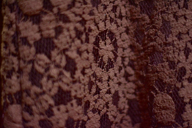 Close-up of a delicate blouse with intricate lace details on a wooden hanger.