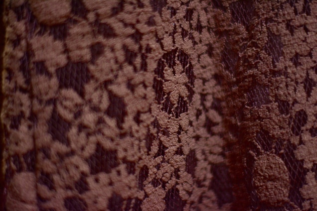 Close-up of delicate embroidery on an ivory lawn fabric showcasing intricate floral patterns.