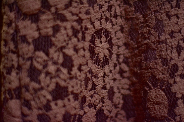 Close-up photo of delicate amaranth-colored lingerie fabric with natural texture.