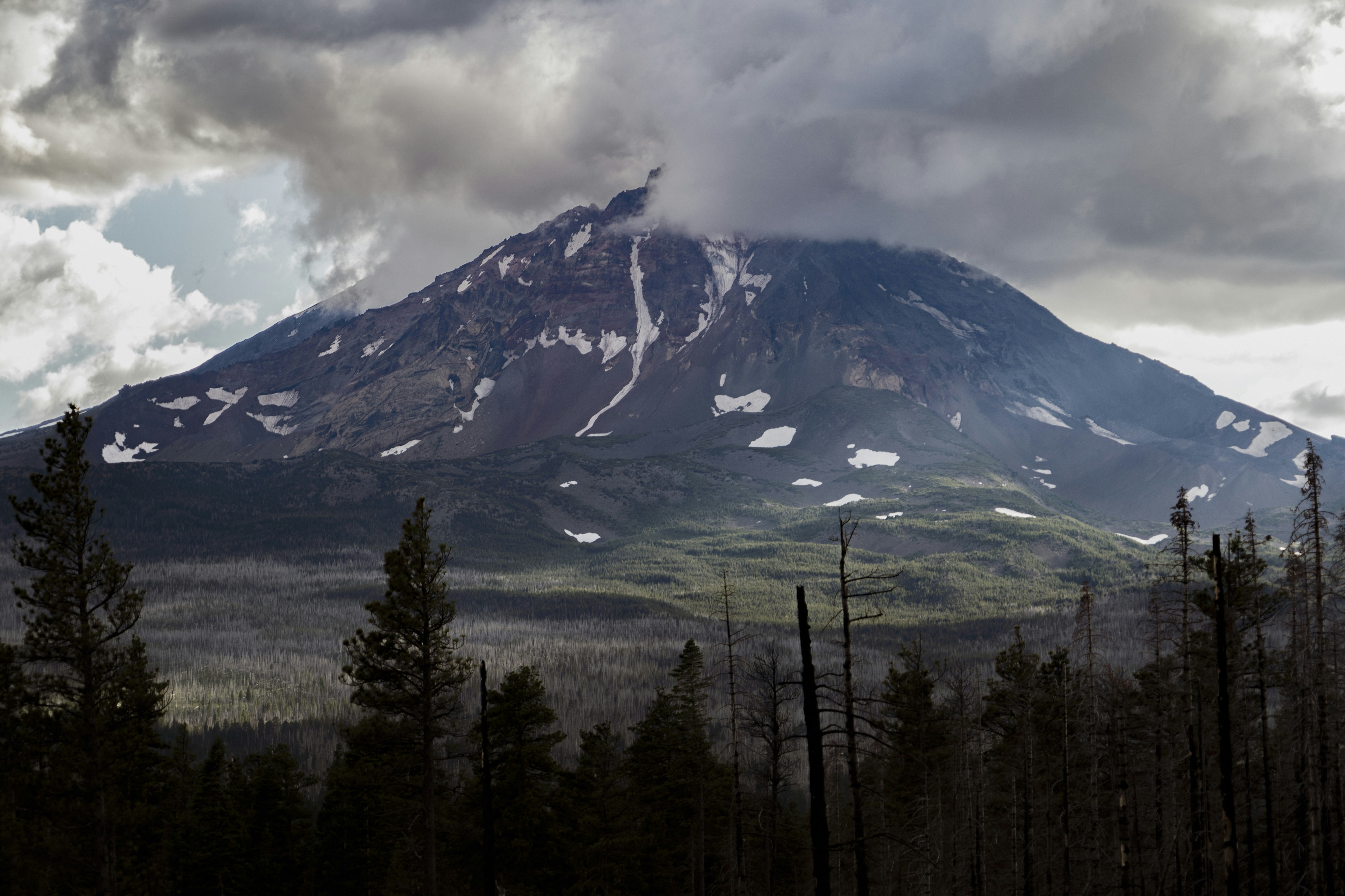 green field viewing mountain under white and blue skies during daytime
