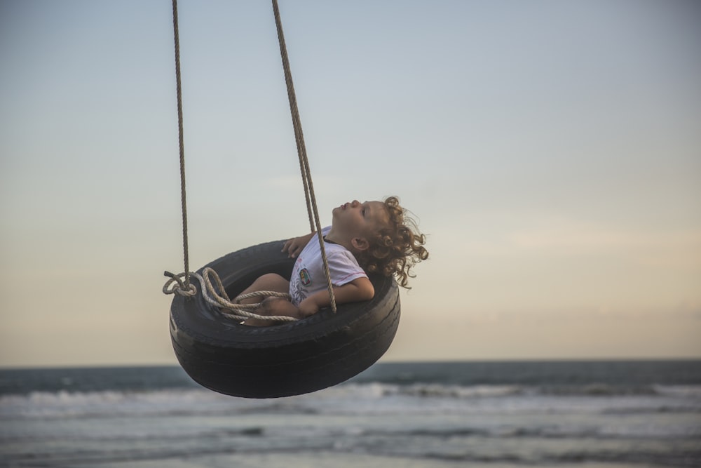 girl sitting on tire swing at daytime