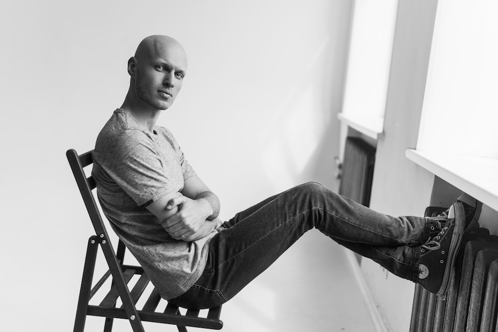 grayscale photography of man sitting on chair