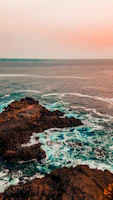 A rugged coastline at sunset with dramatic cliffs and crashing waves.