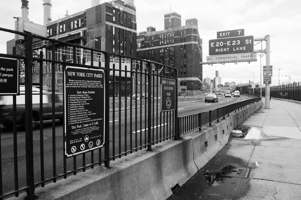 cars on road beside railing, buildings, and signs