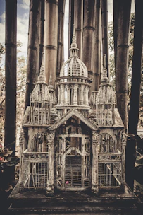 Close-up of a square birdcage with intricate details and a natural wood finish
