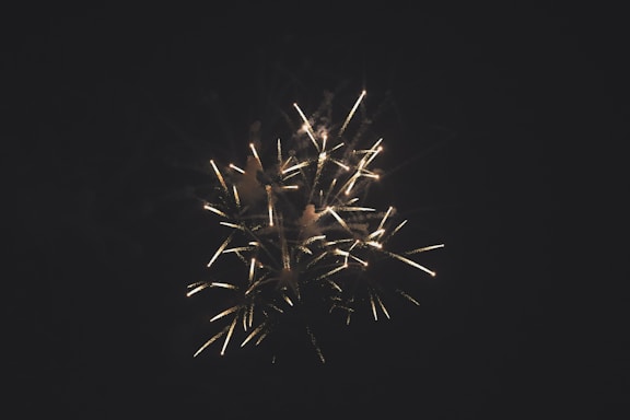 A vibrant display of fireworks with bright, golden sparks spreading across a dark night sky, creating a sense of celebration and excitement.