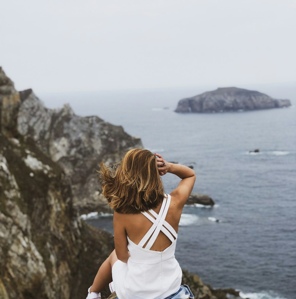 woman sitting and overlooking body of water