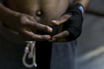A martial artist tying hand wraps before training.