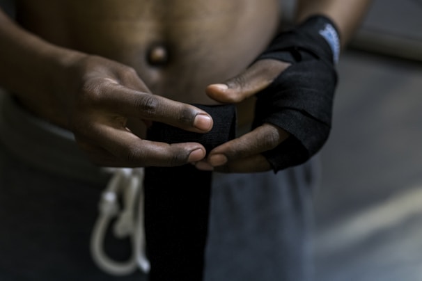 Close-up of a trainer adjusting hand wraps on a fighter’s hands before sparring.