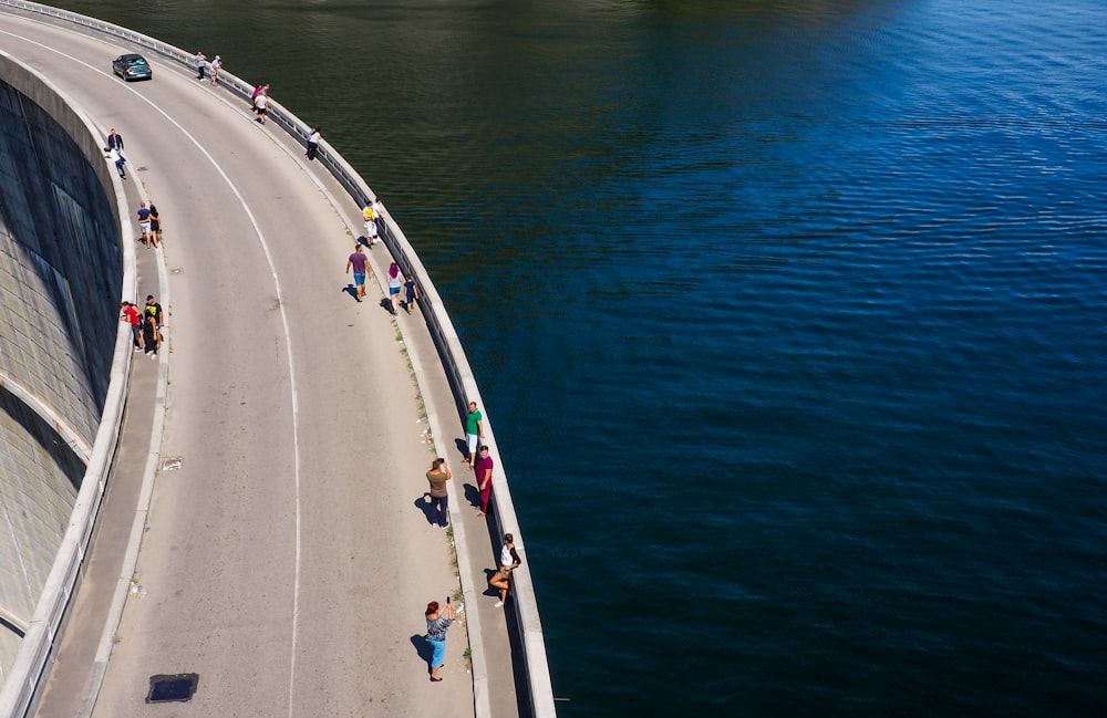 Personnes debout sur une route en béton gris au-dessus d’une eau calme