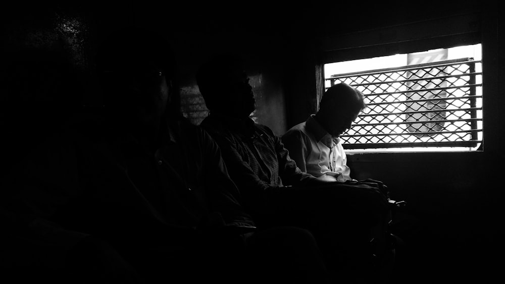a couple of men sitting next to each other in a dark room