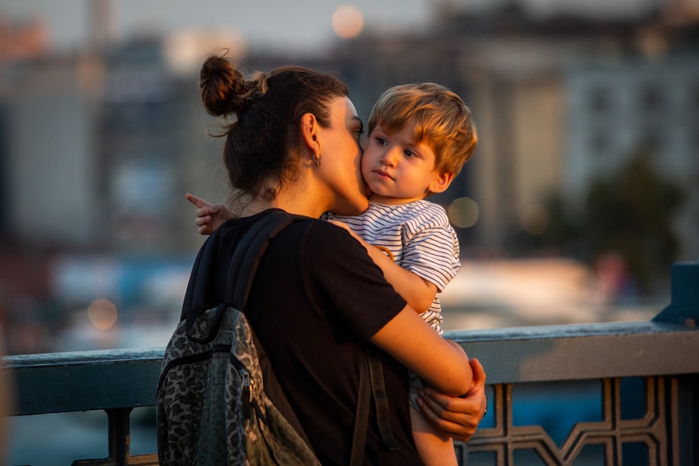 woman wearing black shirt carrying toddler boy