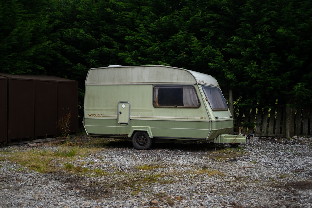 an old camper is parked in a gravel lot