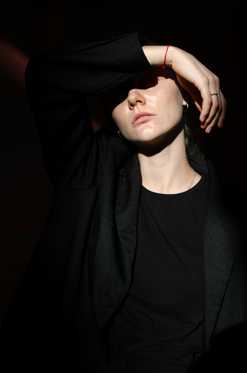 woman wearing black collared top covering her face