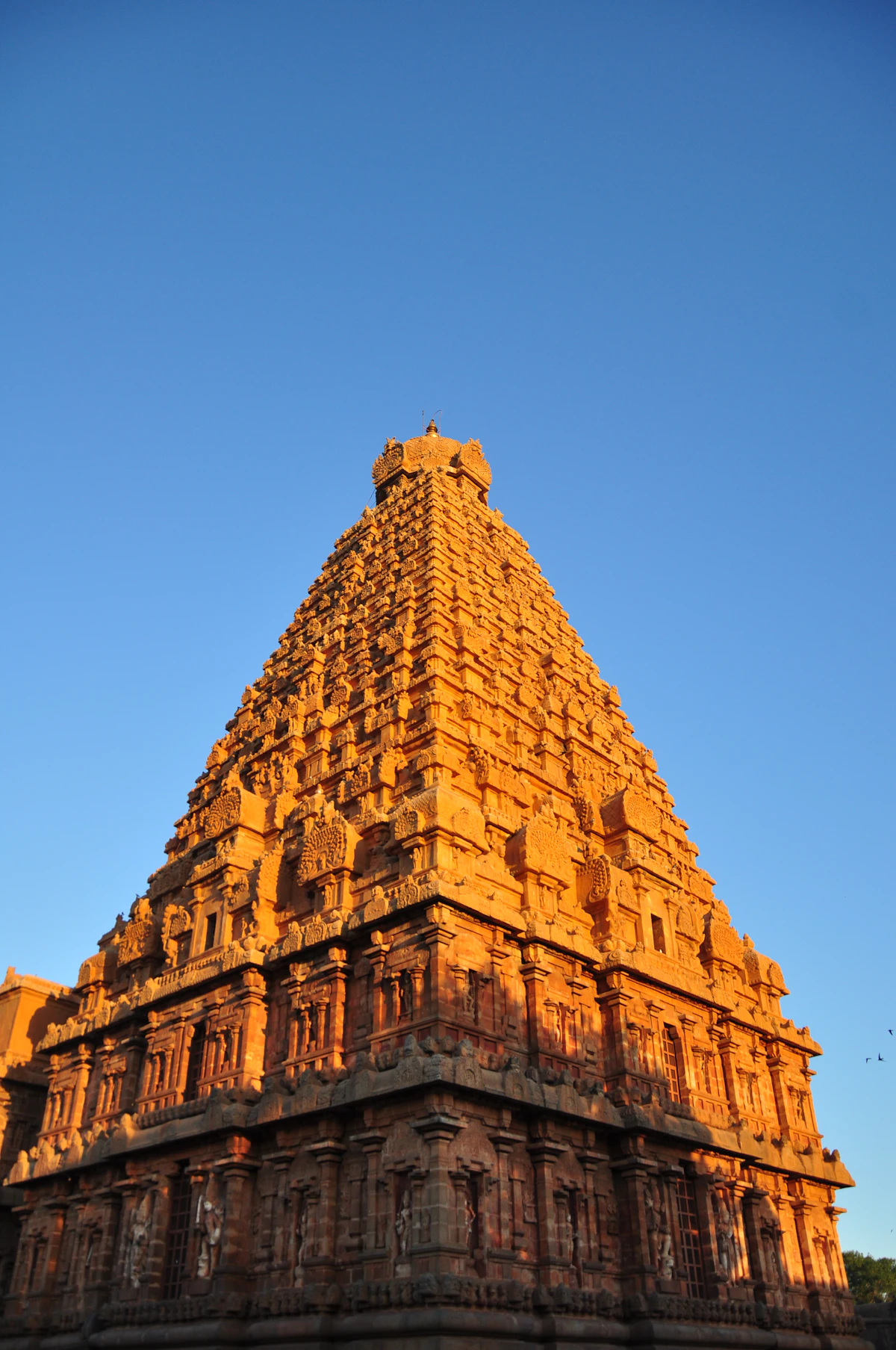 The carved stone tower of an Indian temple in daylight