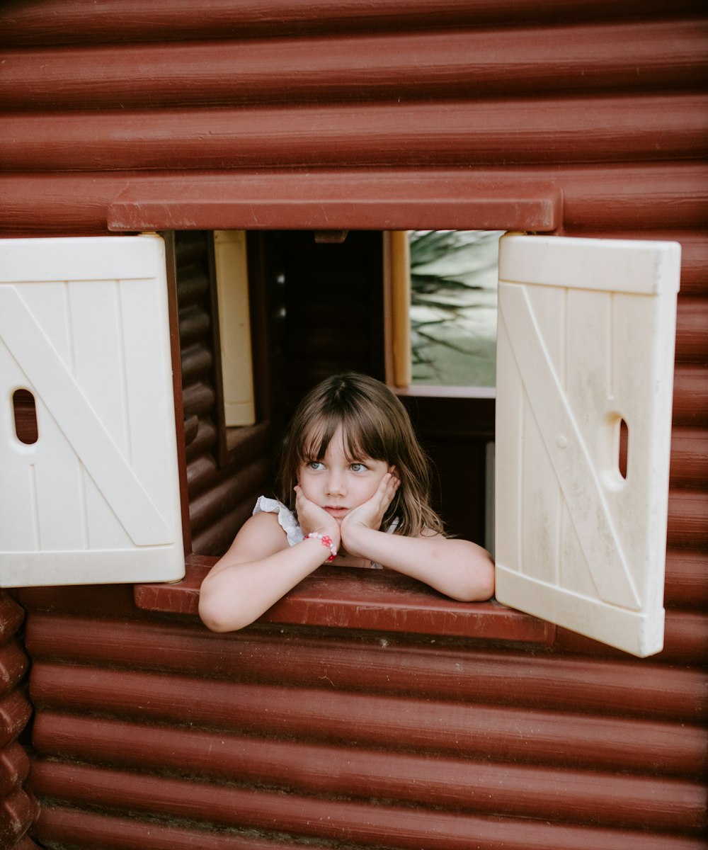 woman leaning on white and brown playhouse window