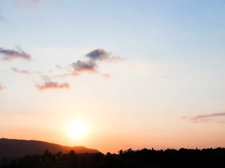 A clear sky with soft clouds and a subtle sunrise over a calm landscape.