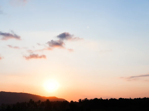 A clear sky with soft clouds and a subtle sunrise over a calm landscape.