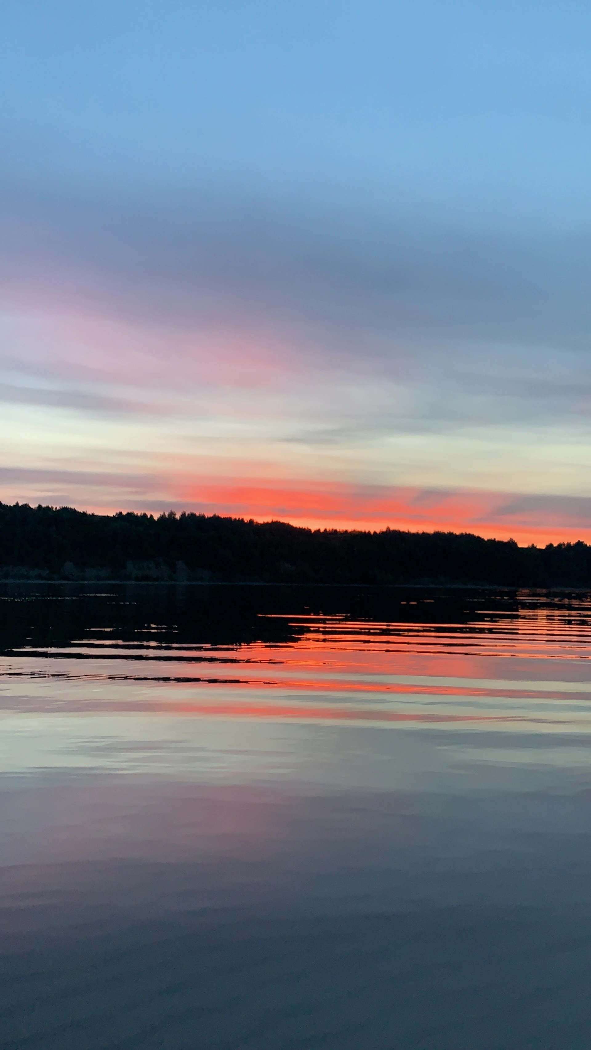 A calm lake reflecting a vibrant sunset sky, symbolizing the search for inner wholeness and fulfillment.