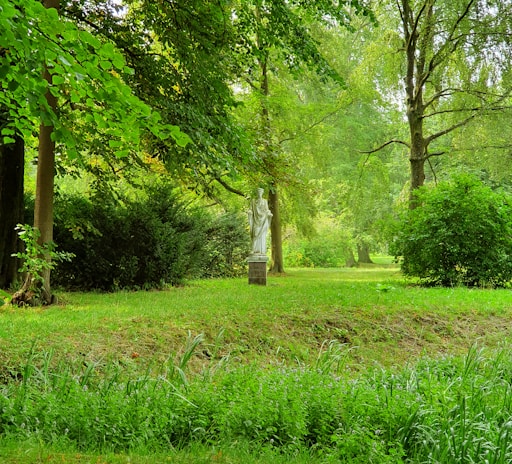 A serene park scene with sculptures surrounded by greenery.