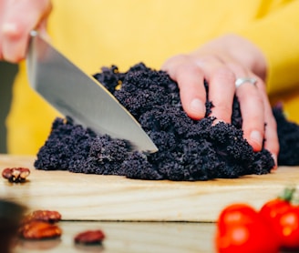 person slicing a black-leafed vegetable