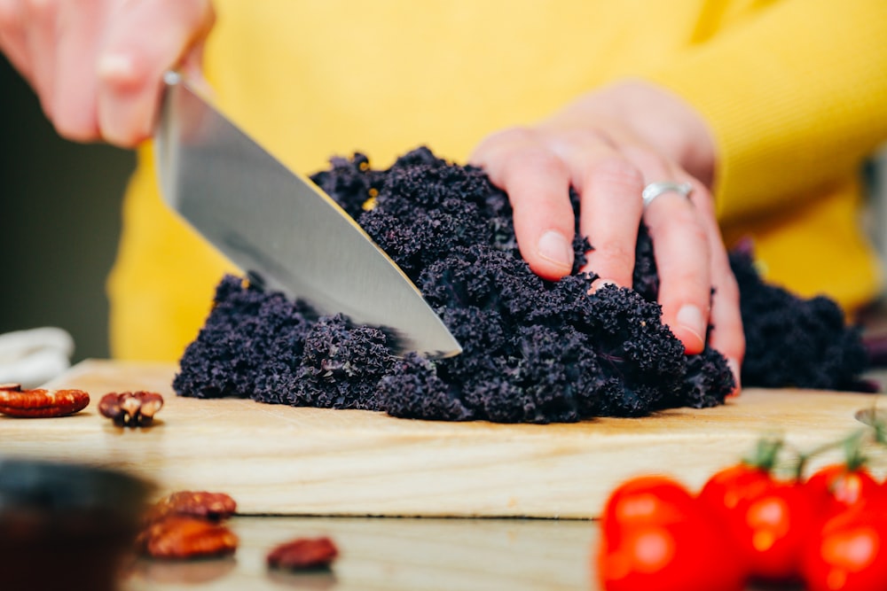 person slicing a black-leafed vegetable