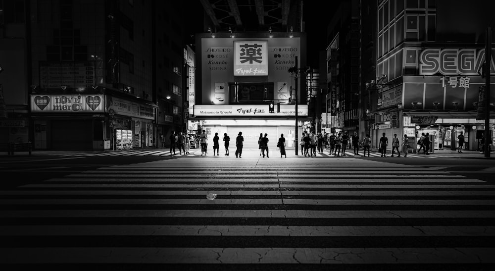 a group of people standing on a cross walk at night