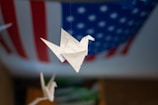 A paper crane flying over a modern office desk with creative tools.