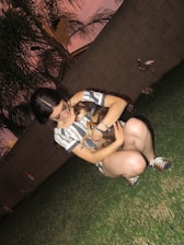 A team member scooping dog poop from a green, sunny backyard.