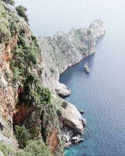A panoramic view of the coastline from a boat, showing the vibrant blue sea meeting the rugged cliffs.