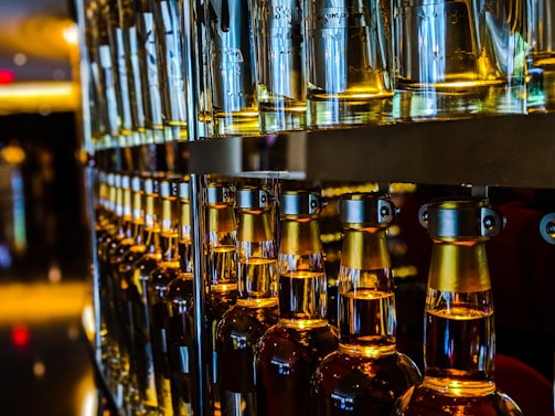 Rows of glass bottles filled with fragrant oils, labeled and lined up in a warehouse setting.