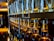 Rows of glass bottles lined up on rustic wooden shelves in a distillery setting.