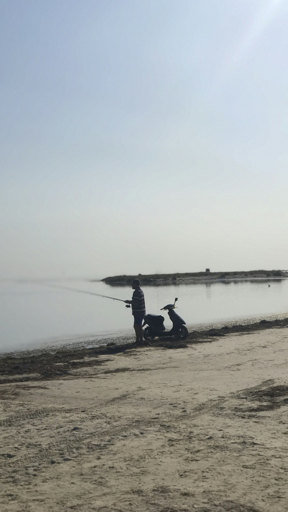 person fishing in seaside with motor scooter
