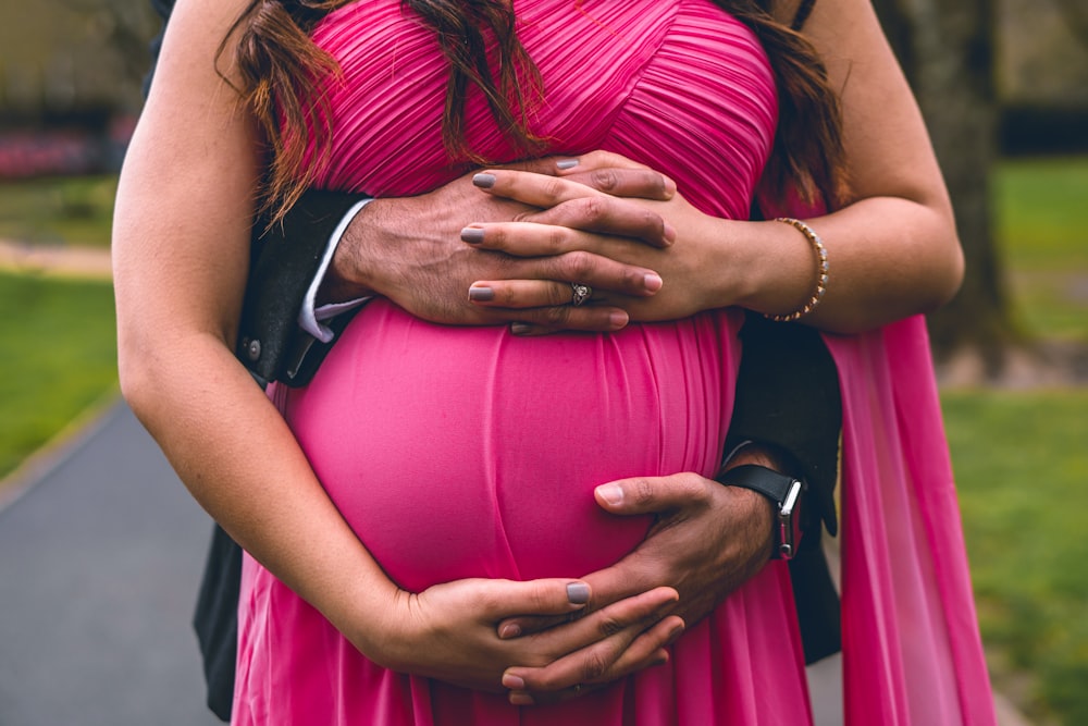 man hugging woman wearing pink dress