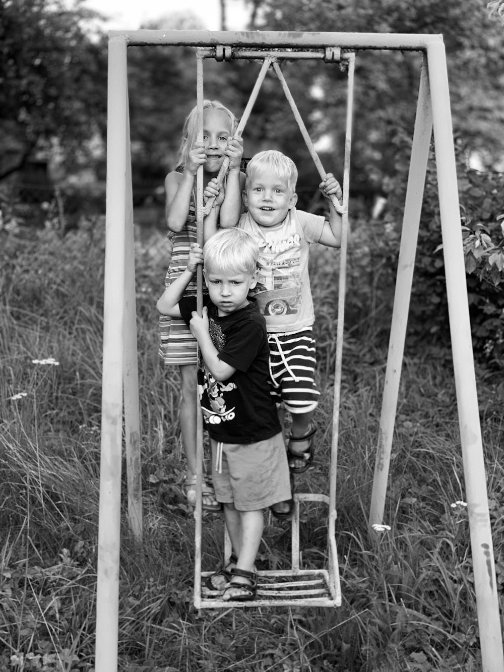 three kids standing on swing