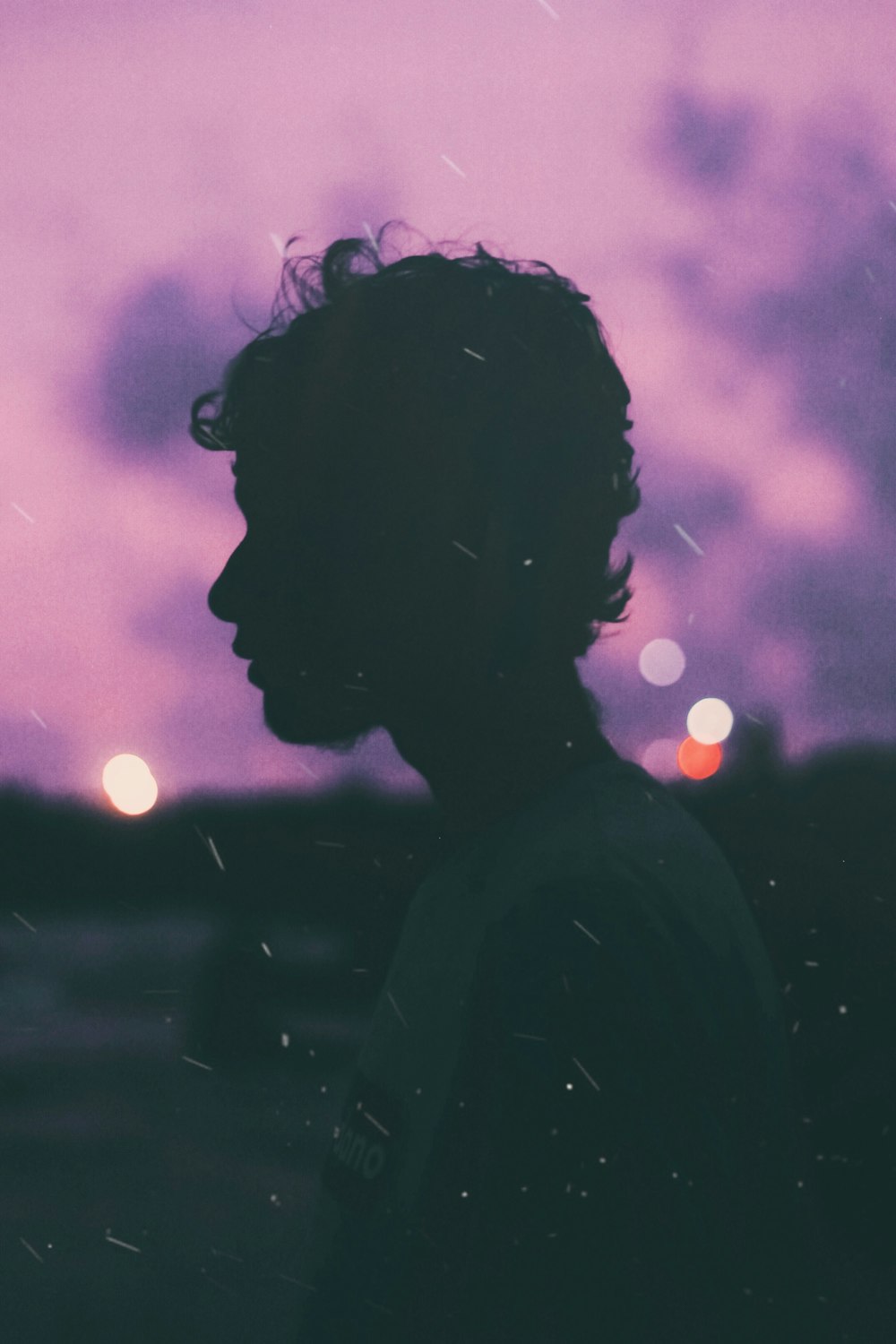 Una persona parada frente a un cielo púrpura